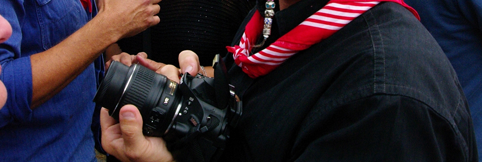 Een fotograaf met camera en rood-witte halsdoek, op de markt